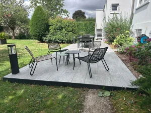 Terrasse contemporaine en grés céram imitation bois, mariée à un jardin fleuri. Un espace de vie extérieur conçu par Créalia pour allier élégance, confort et résistance au climat.